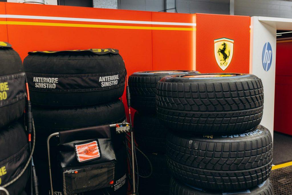 Stack of racing tires in Ferrari-themed garage, focus on motorsport equipment.